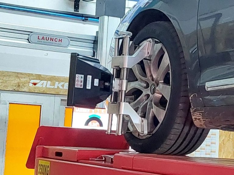 Coche gris aparcado cerca de un neumático de alto rendimiento con etiqueta visible.