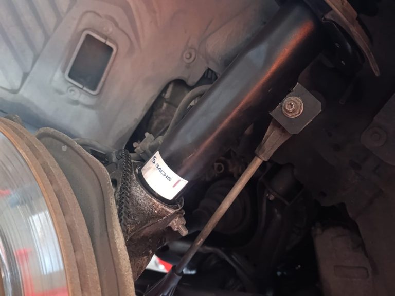 Vista cercana de un eje de transmisión y amortiguador componentes en un vehículo.